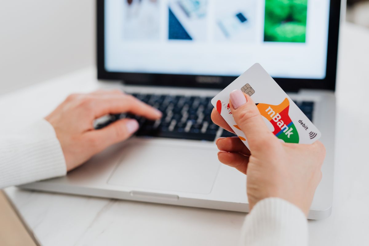 Hands using a credit card with a laptop